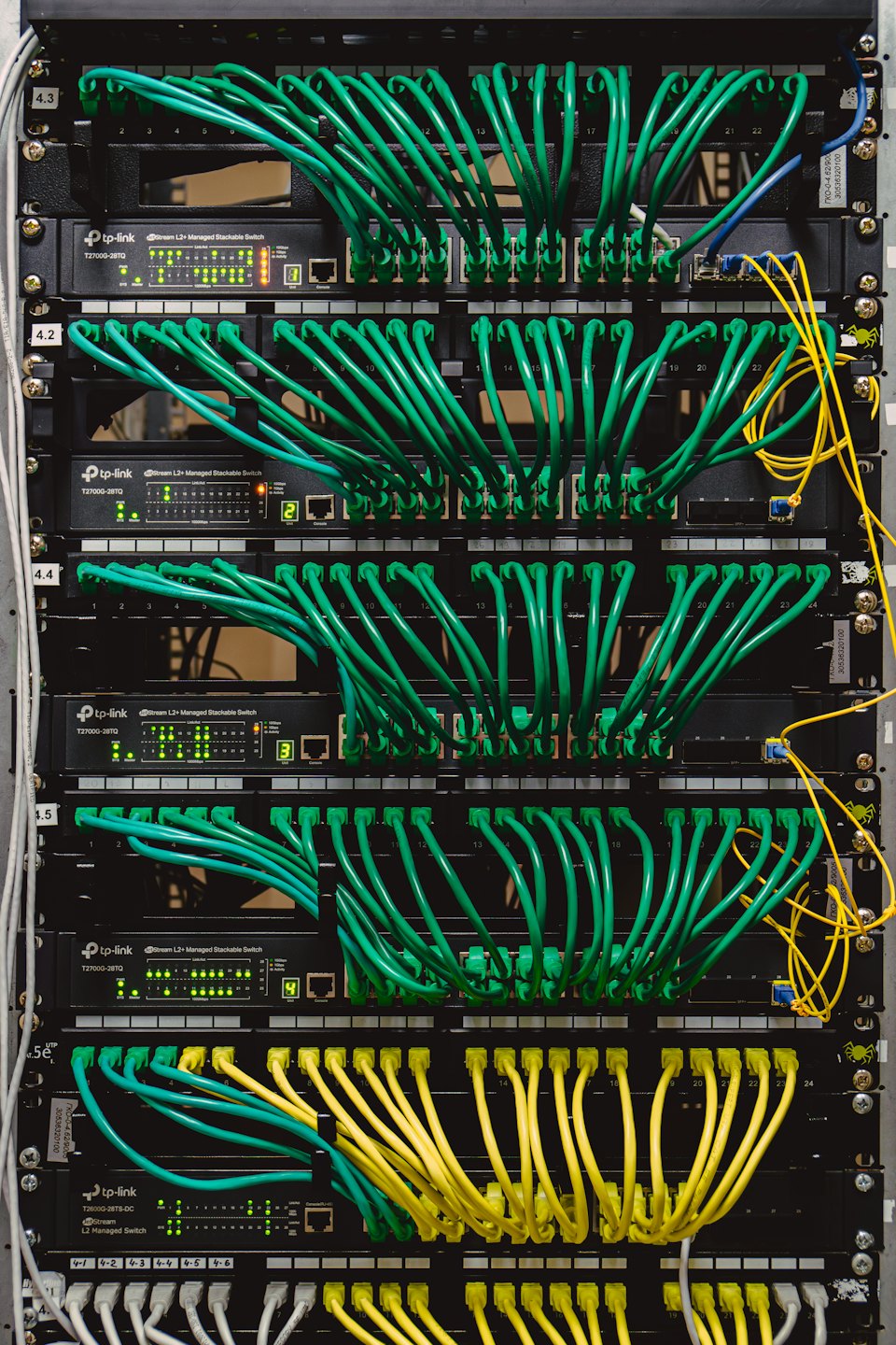 Stacked network switches with many plugged-in ethernet cables.
