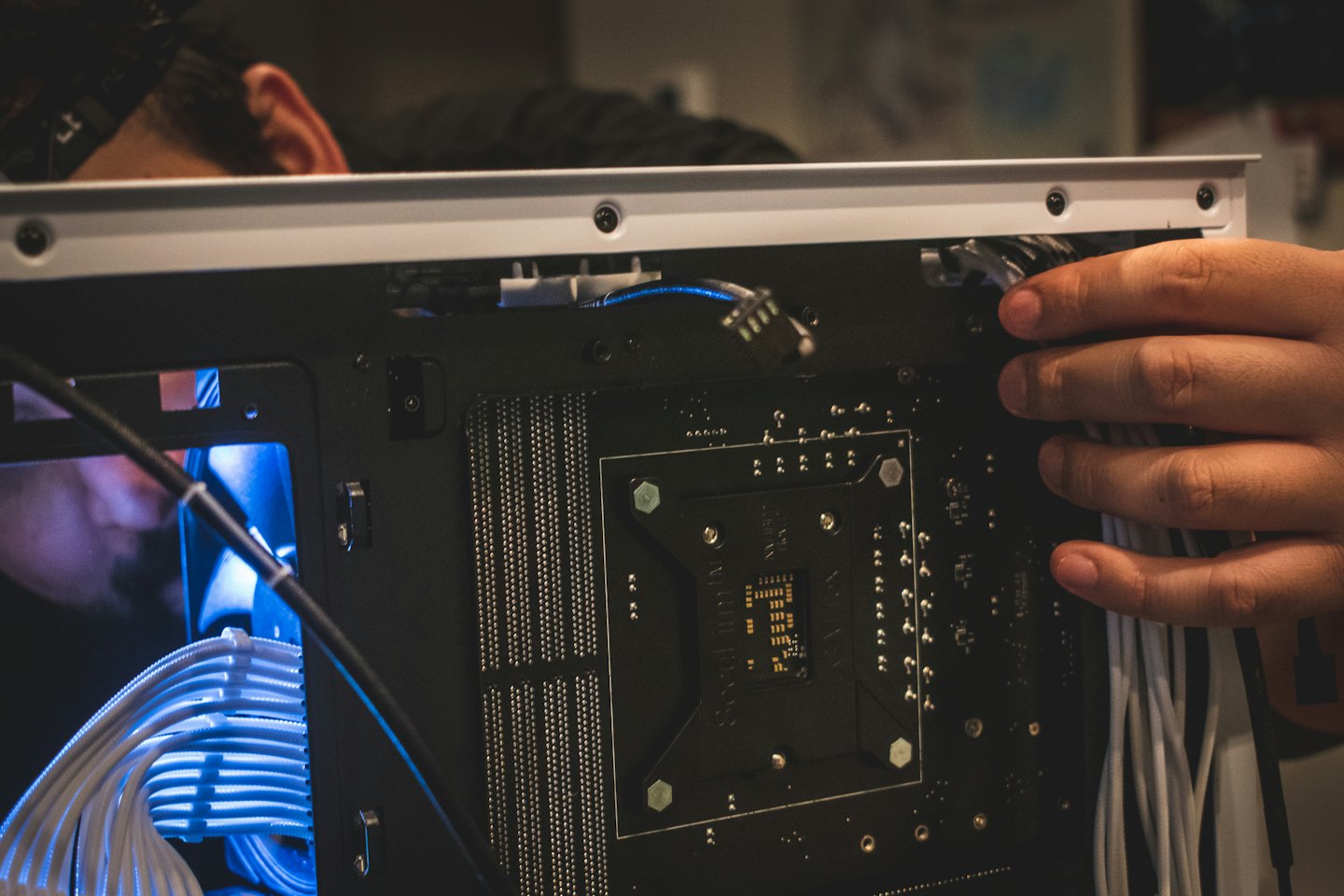 Technician organizing white cables inside a computer tower.
